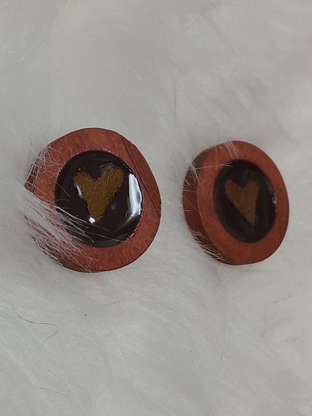 Handmade earrings on a wooden base with a piece of punched-out tree leaf
